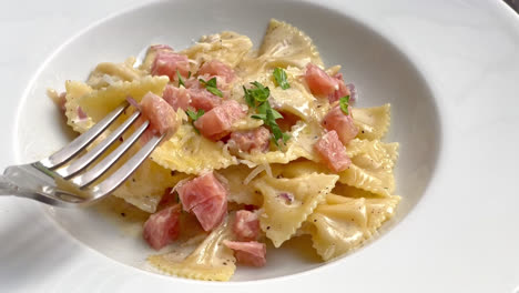 Carbonara-Farfalle-Nudeln-Mit-Schinkenwurst-Auf-Weißem-Teller