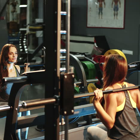 young beautiful woman in a gym doing sit-ups with a bar in front of a mirror. women's athletics square video