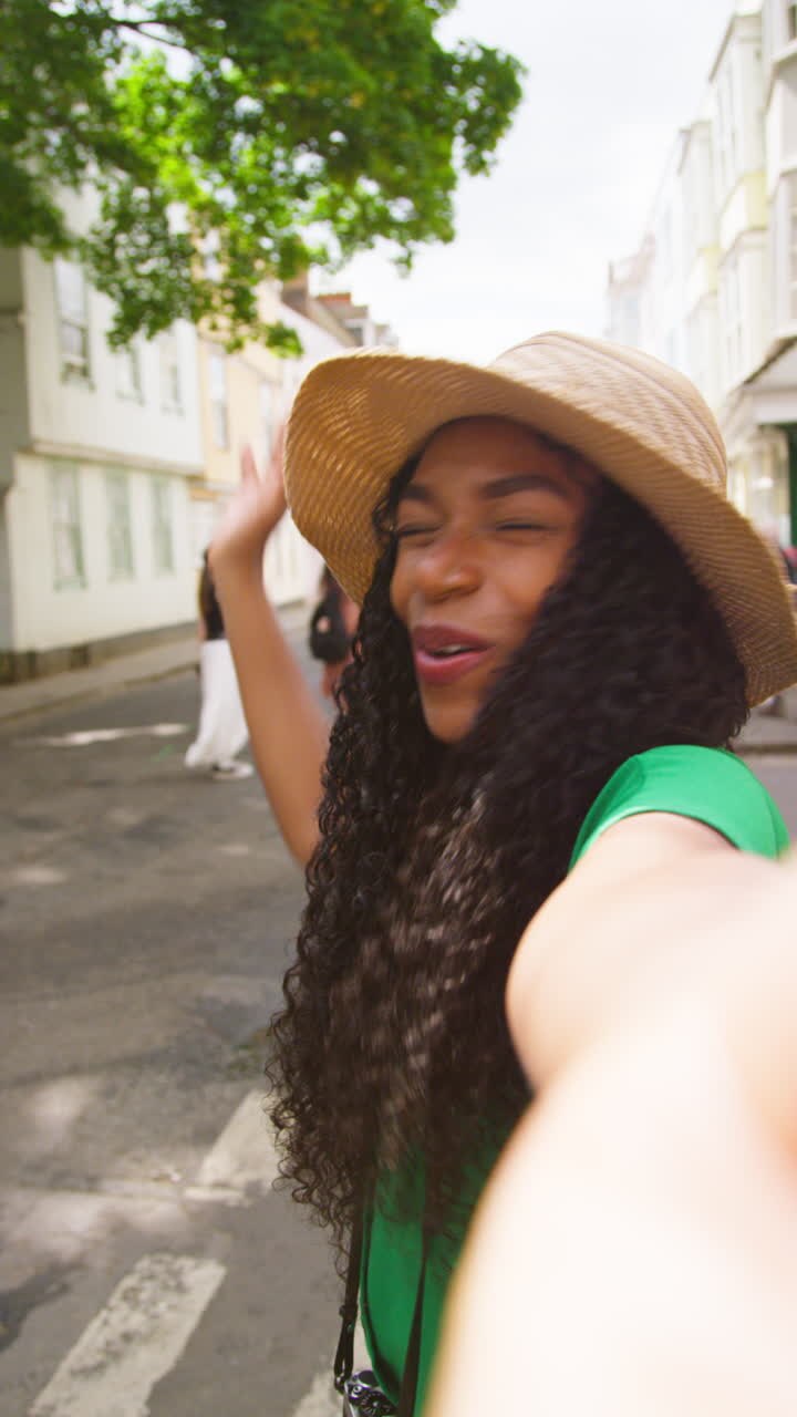 Vertical Video POV Shot Of Female Tourist On Vacation In Oxford UK Exploring City Walking Along Holywell Street Posing For Selfie On Mobile Phone 1
