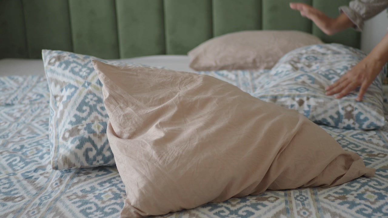 Close-up of Hands Arranging Pillows on a Bed