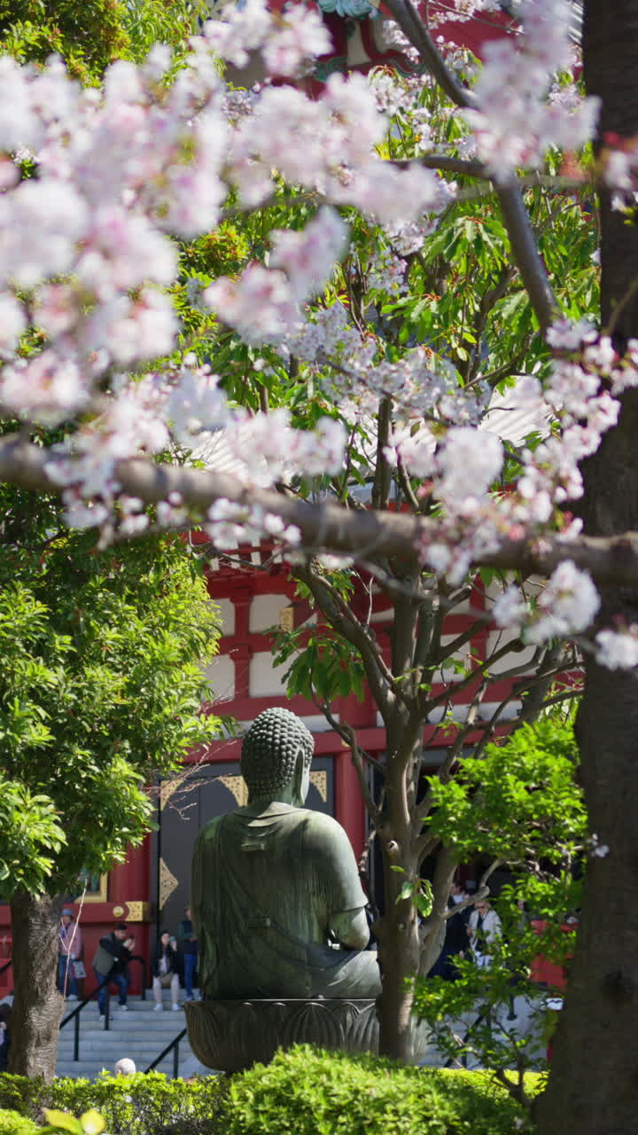 Buddhist sculpture surrounded by trees in Asakusa, Tokyo, Japan. Vertical