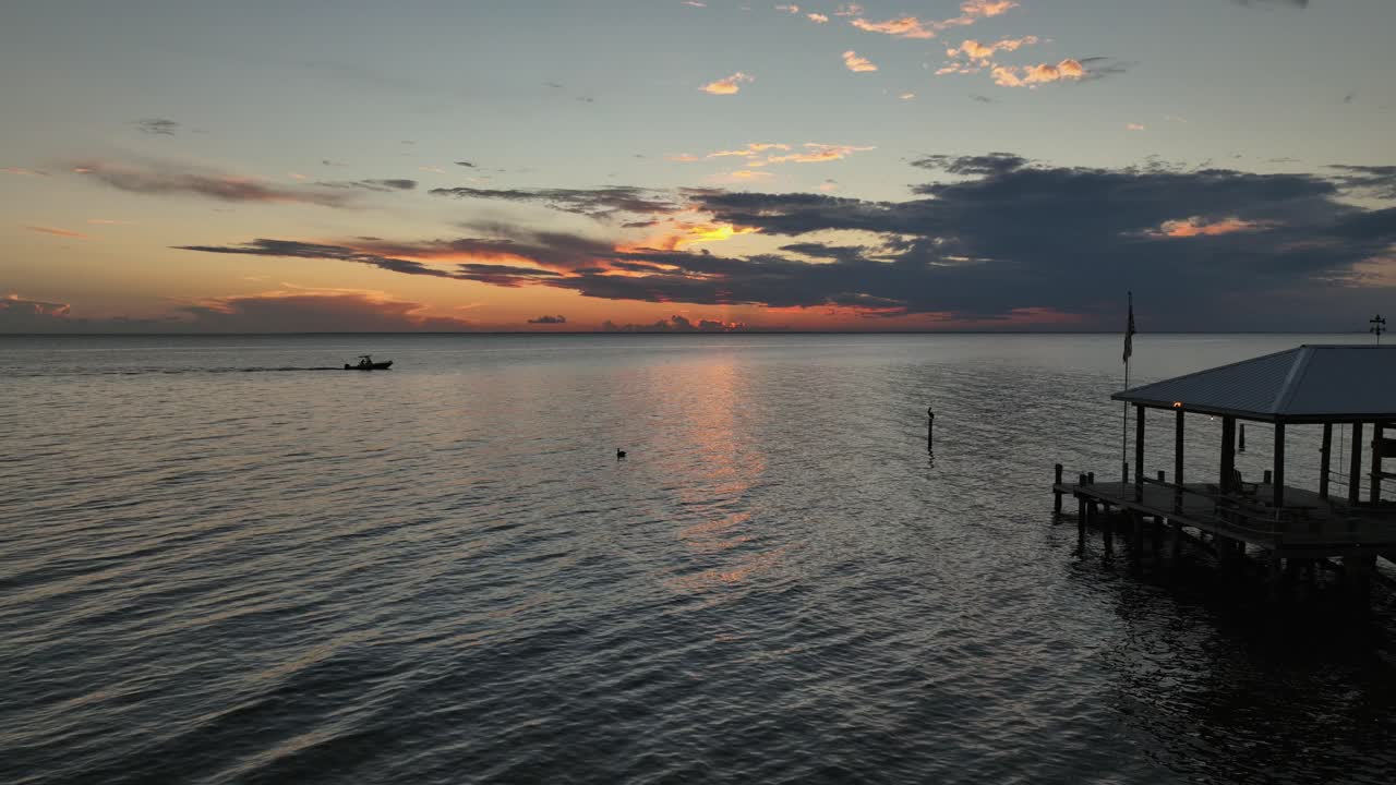 일몰, 선착장, 펠리컨 및 어선이 지나가는 여전히 공중 전망