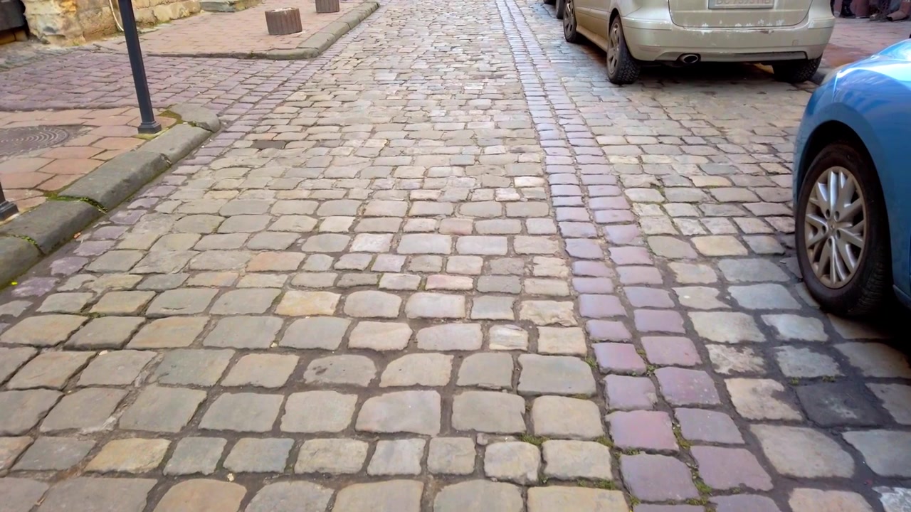 Old street of paving stone and parked cars.