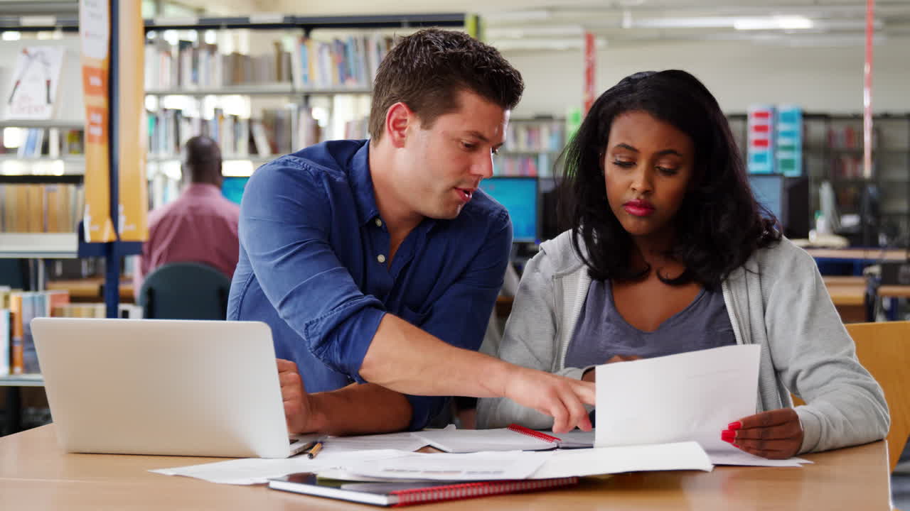 dos estudiantes maduros trabajando en una computadora portátil en la biblioteca de la universidad