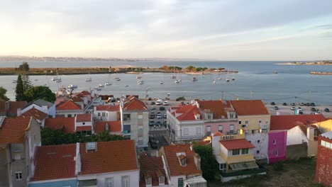 toma aérea volar de regreso a través de los árboles sobre la bahía de seixal y edificios - portugal