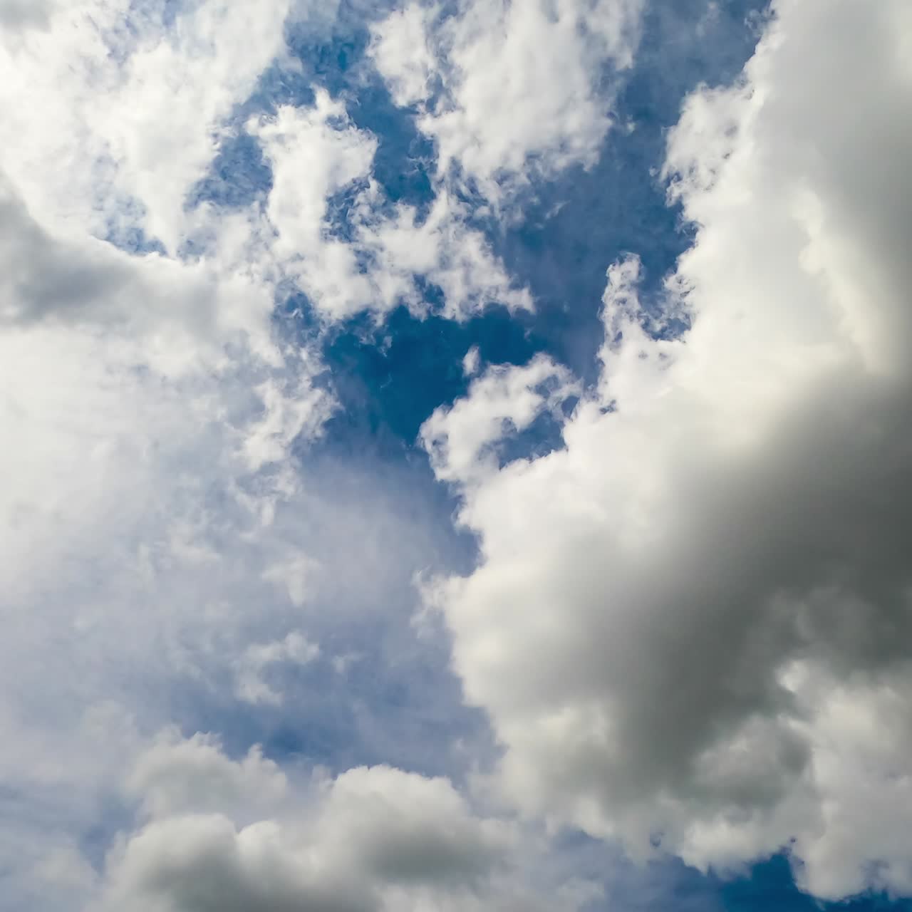 Cumulus clouds floating by the bright blue sky. White and grey clouds fully covering the horizon. Timelapse