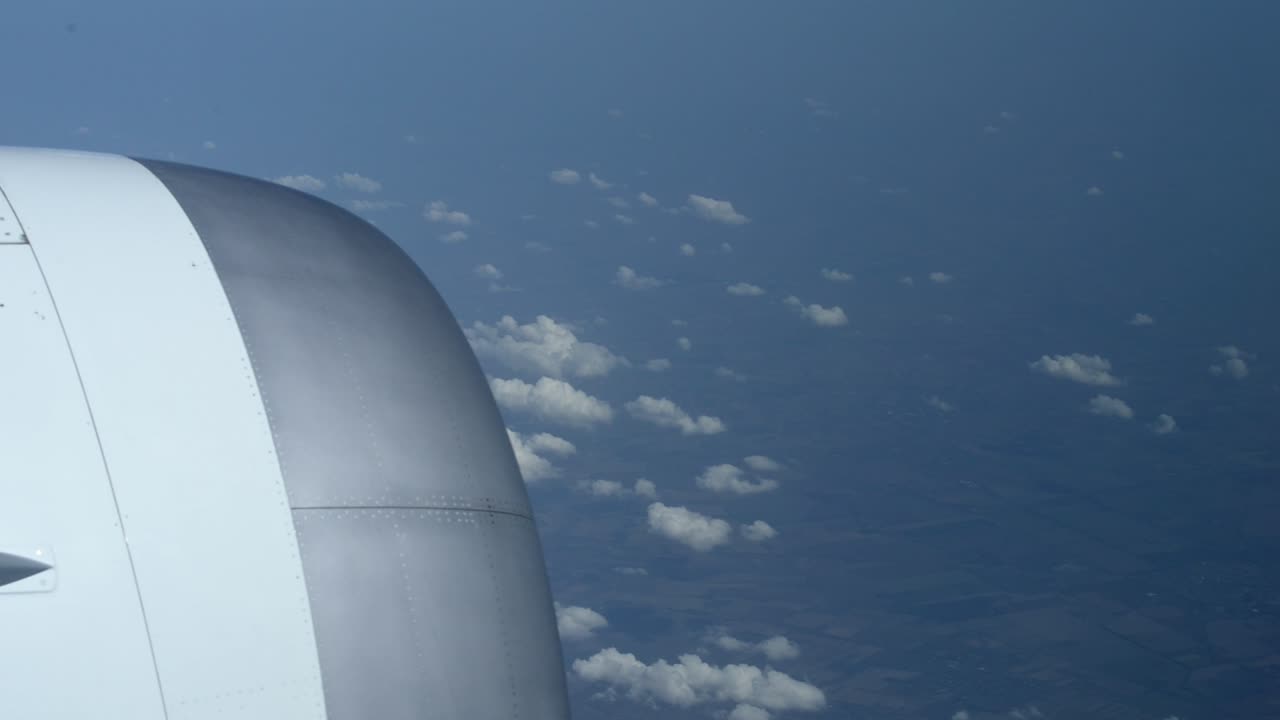 몇 구름 아래 평평한 풍경 위를 높이 비행하면서 비행기 창 밖을 봅니다.