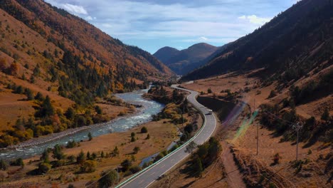 car driving on the road along the mountain valley during autumn