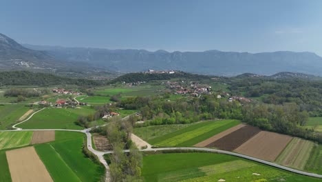 wide aerial pan of green hilly farmland and vipava village in slovenia