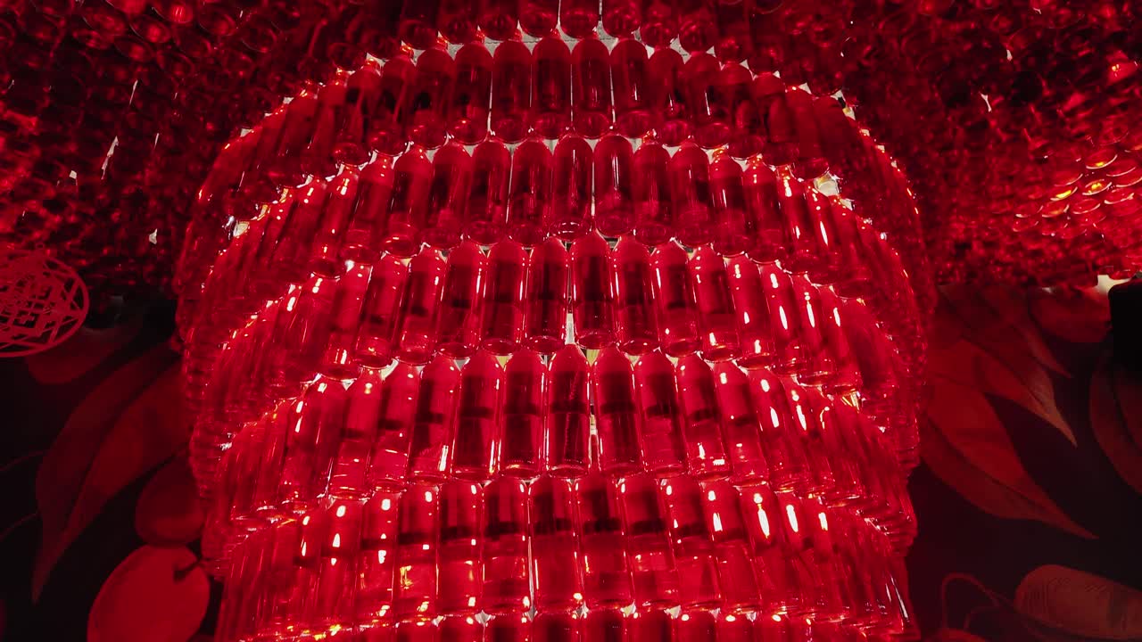 Glass bottles filled with red liquid hung on the wall and ceiling, illuminated by lamps. All this beauty is installed in the bar.
