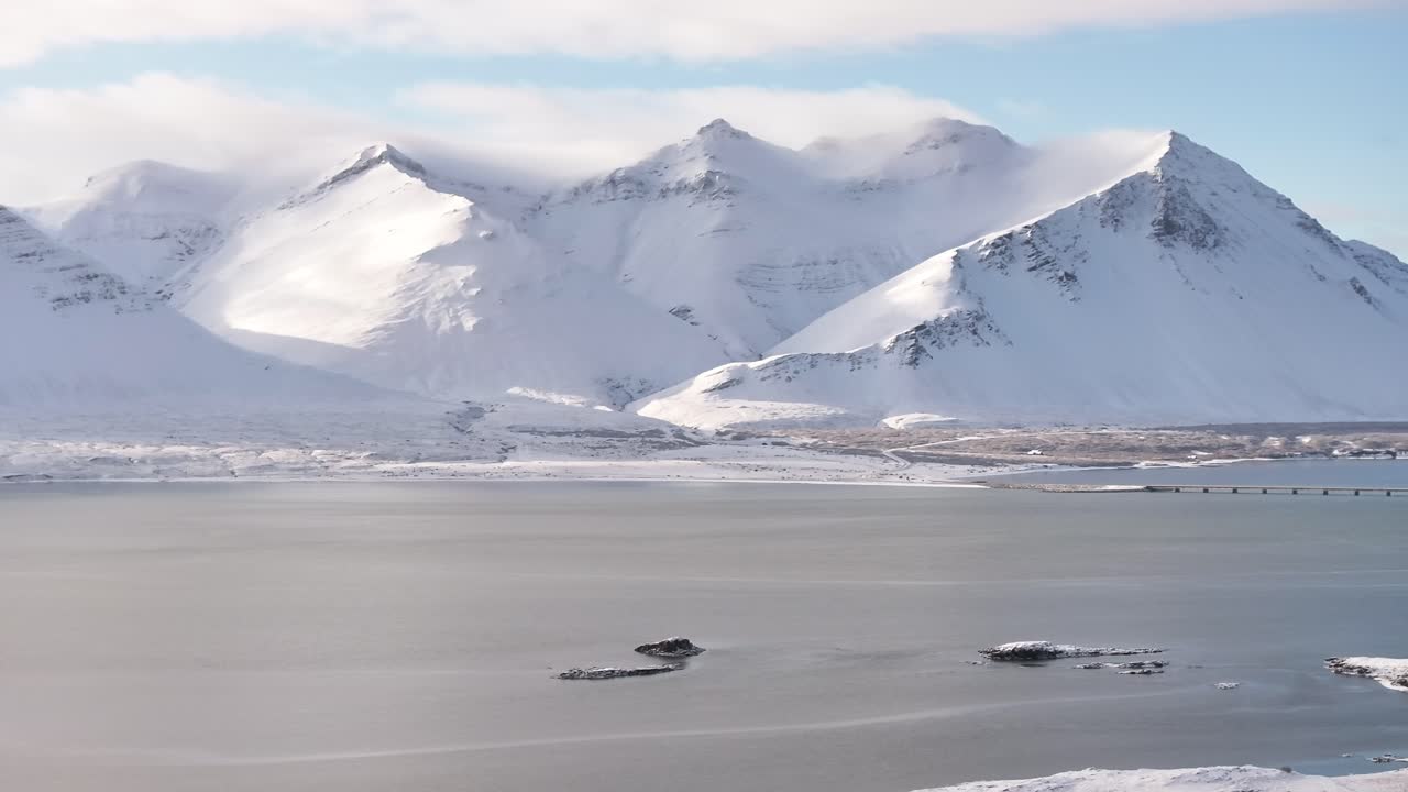 Snow covered peaks of Hafnarfjall and Baula rise above icy Borgarfjörður near Borgarnes Iceland