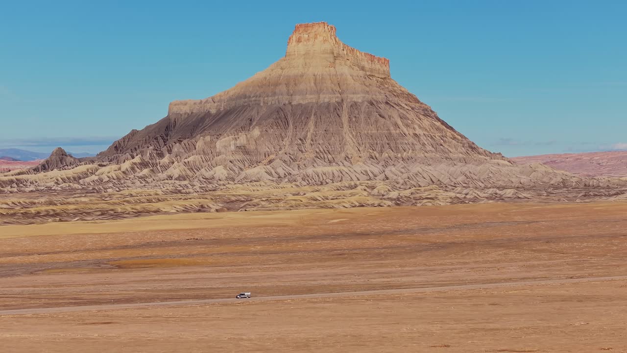 Factory Butte che si erge solitario attraverso una pianura desertica aperta nel paesaggio arido dello Utah, ripreso da drone.