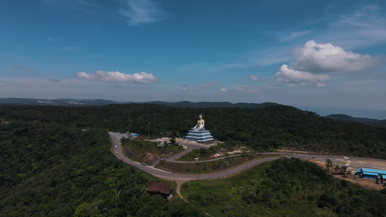Big golden Buddha statue Yeah Mao Statue in the middle of the green nature of Bokor National Park on a clear sunny day in Cambodia. aerial drone panning shot