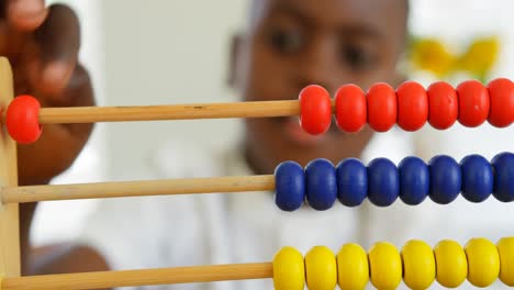 front view of little black boy studying with abacus in a comfortable home 4k