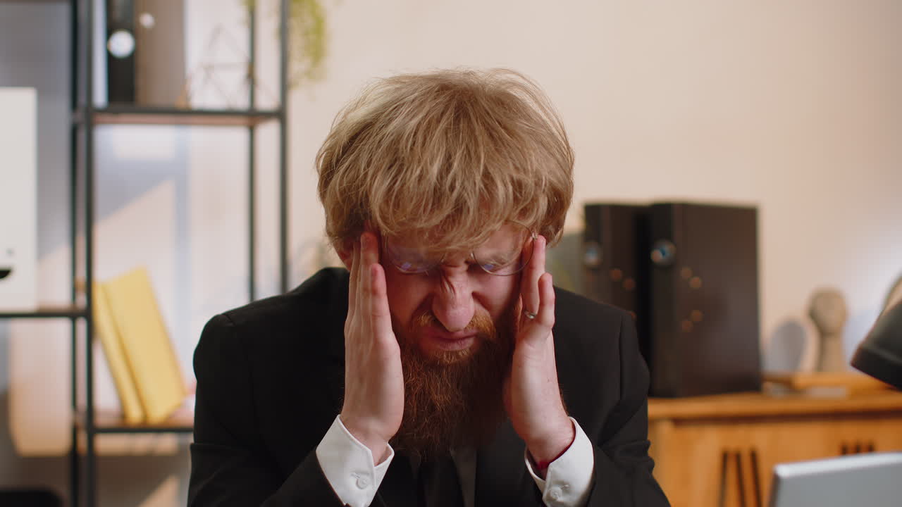 Tired young business man suffering from headache problem tension migraine stress at home office