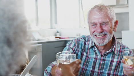 Pareja-De-Ancianos-Haciendo-Un-Brindis-Con-Vino-Mientras-Una-Familia-Multigeneracional-Se-Reúne-Para-Comer-En-Casa