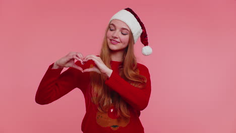 Smiling-girl-in-Christmas-sweater-makes-heart-gesture-demonstrates-love-sign-expresses-good-feelings