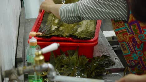 leaves for wrapping asian rice triangles being trimmed to remove sharp tips during food prep