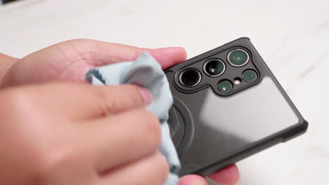 close-up of a person cleaning up her smart mobile phone with a clean blue washcloth