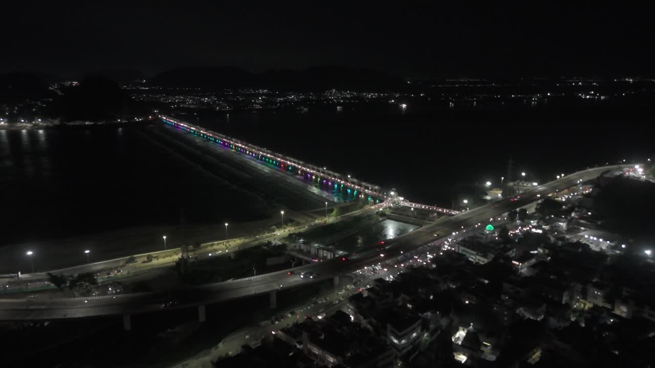 Aerial views of Vijayawada at night offer a breathtaking spectacle. The Krishna River, illuminated by the Prakasam Barrage A bustling metropolis near Amaravati, the capital of Andhra Pradesh