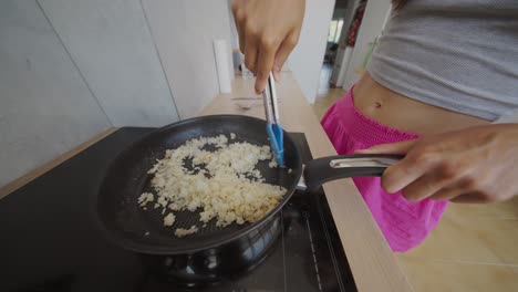 woman cooking food in a frying pan on an induction cooktop