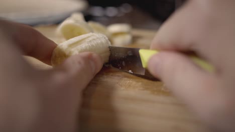 cerca de una mujer cortando un delicioso plátano en una tabla de cortar de madera