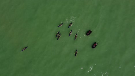 Aerial-drone-video-top-down-view-of-a-rowing-team-of-sport-kayak-practicing-in-the-ocean-on-a-sunny-day