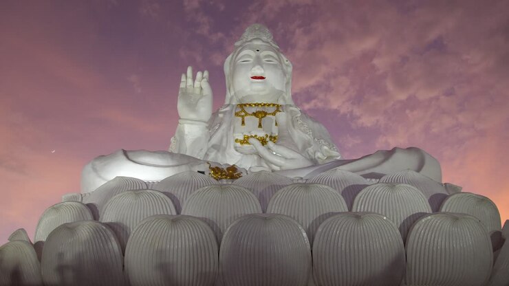 Sguardo verso l'alto sull'enorme statua bianca di Guan Yin, la dea della misericordia al Wat Huay Pla Kang a Chiang Rai, Thailandia. - Inquadratura dal basso