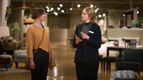 Friendly-female-salesperson-guiding-customer-into-store-engaging-in-conversation