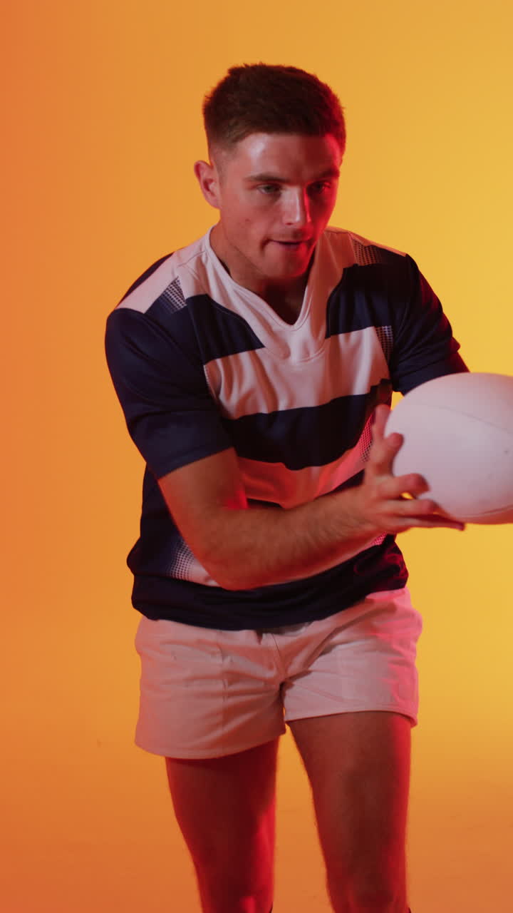 video vertical de un jugador de rugby caucásico atrapando una pelota de rugby sobre la iluminación rosa