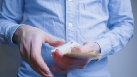 man counting 50 euro, paper money bills and offers them to someone