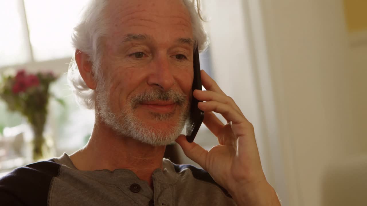 Senior man talking on mobile phone at home 4k