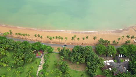 Von-Oben-Aufgenommene-Drohne-Vom-Strand-In-Emilia-Mit-Brechenden-Wellen-Und-Vorbeifahrenden-Autos-Auf-Einer-Straße