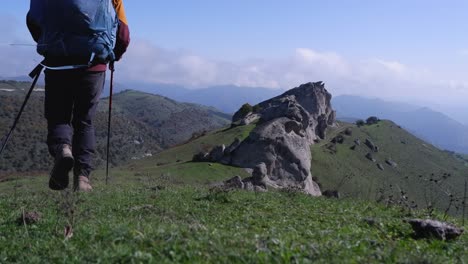 excursionista de montaña con una mochila grande se aleja de la cámara de bajo ángulo
