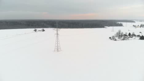 slow aerial over winter fields with a telegraph tower in a field