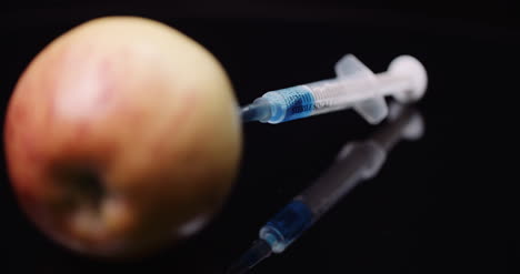 jeringa de modificación genética de alimentos inyectando liqquid en concepto de modificación de apple gmo 5