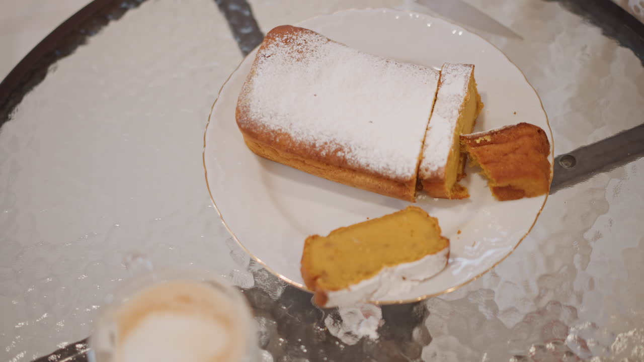 Overhead pumpkin loaf beside latte cup, dusting of powdered sugar on golden slice, glass table reflection, soft bokeh background, barista presentation for cafe menu, warm commercial vibe, closeup