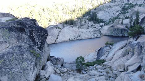 imágenes cienmáticas de drones de 4k que vuelan por acantilados rocosos en el lago alpino en lo alto del desierto en la cordillera de sierra nevada en california llena de aventuras acampando con amigos y familiares en verano