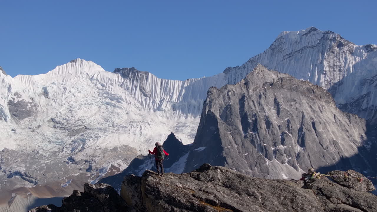 Un escursionista sale verso la vetta Nangkartshang, vicino a Dingboche, durante il trekking al Campo Base dell'Everest in Nepal. Ghiacciai innevati e l'Ama Dablam creano uno spettacolare sfondo himalayano.