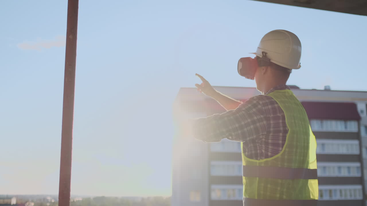 ingeniero constructor en el techo del edificio al atardecer se encuentra en gafas vr y mueve sus manos usando la interfaz del futuro. ingeniero futurista del futuro. la vista desde la parte de atrás