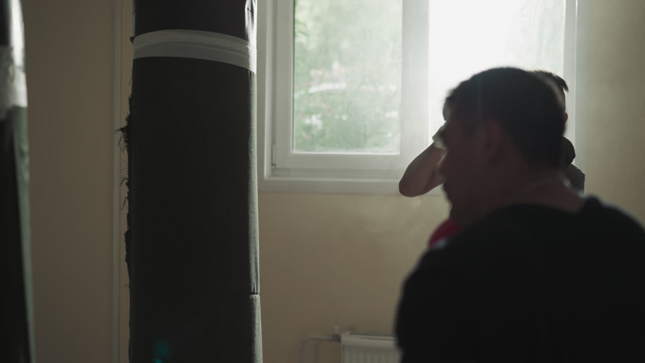 Kick-boxers beat punching bags together in sports club. Professional sportsmen kick and punch hanging equipment in fighting team gym slow motion