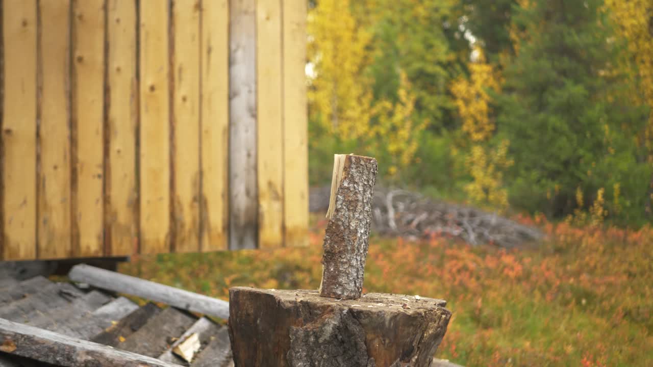 hombre cortando leña usando un hacha fuera de la leñera en medio del bosque durante la temporada de otoño - gran diapositiva en cámara lenta