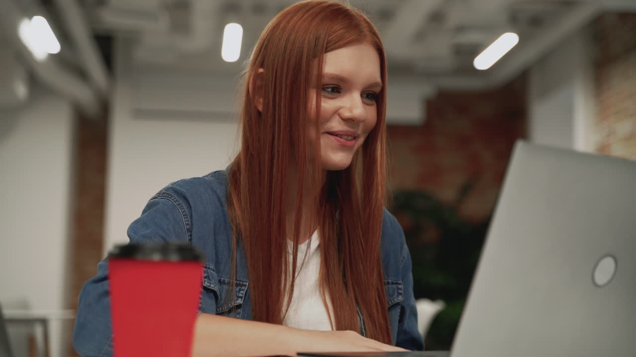 Young female worker having a video call in the office. Copy space. Businesswoman teleworking with laptop.