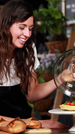 camarera sonriente mostrando pastel de fresa
