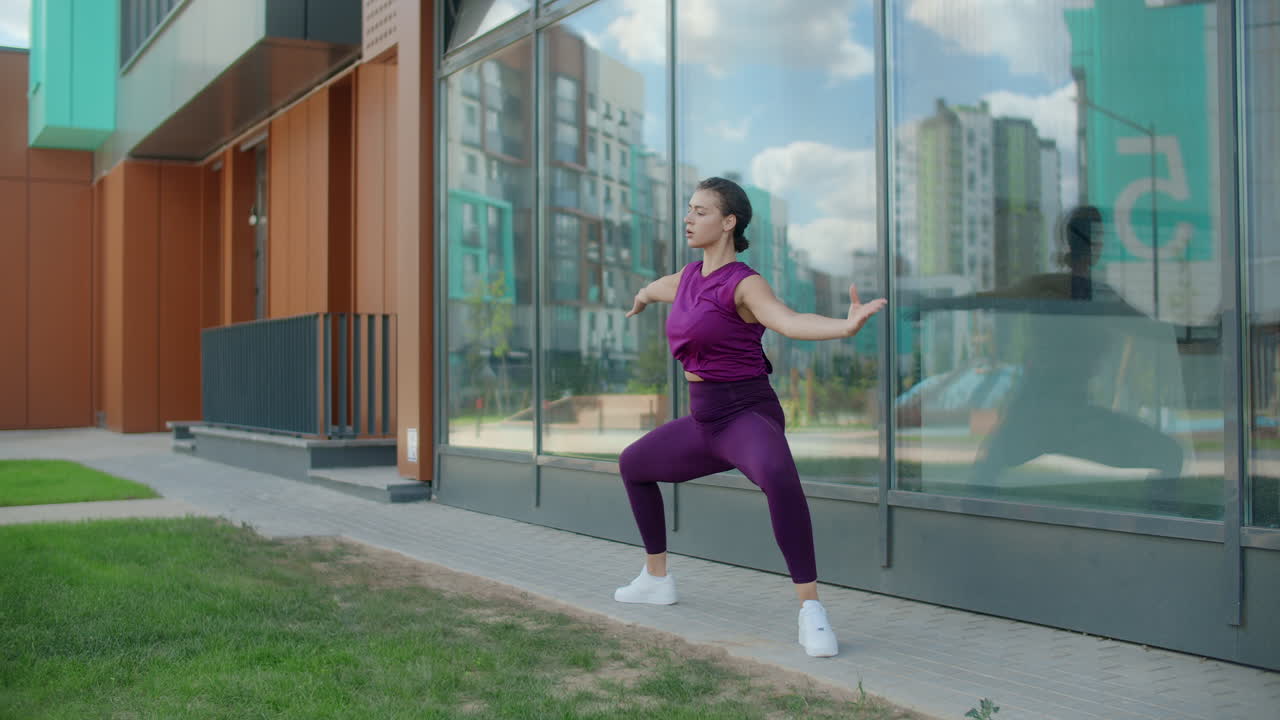 Woman practicing yoga outdoors by a building