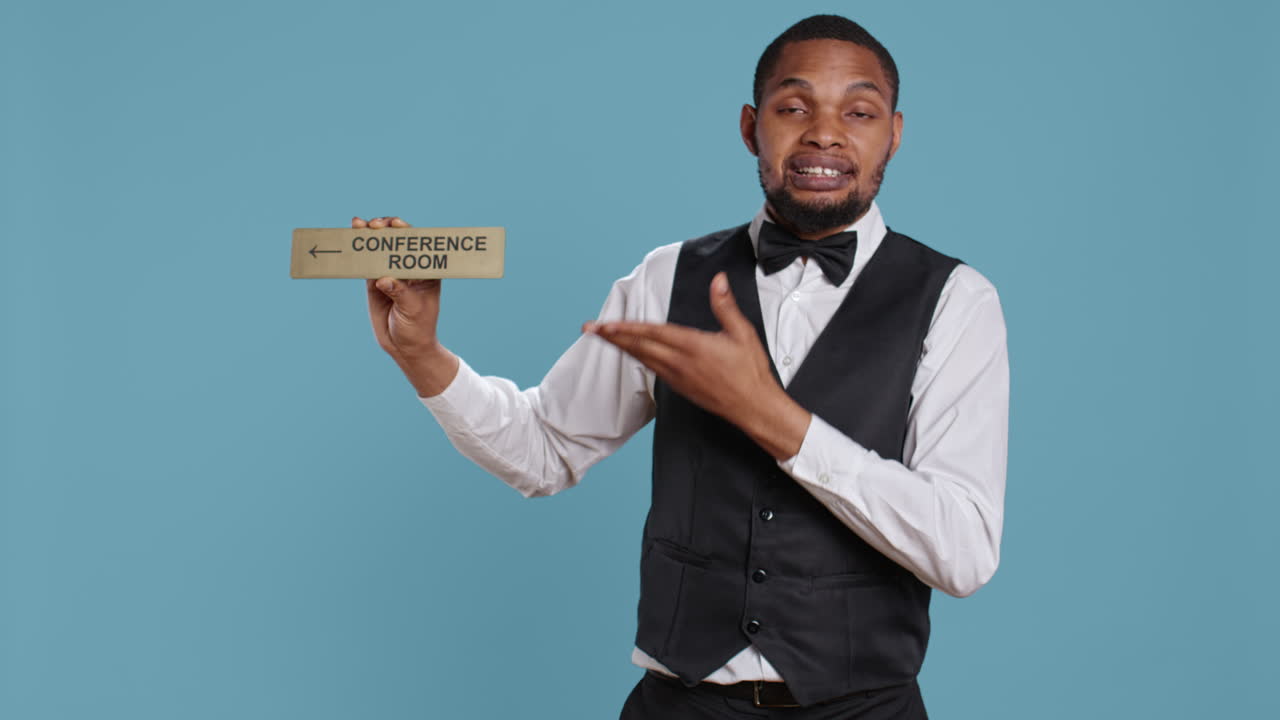 el conserje del hotel usando un indicador de pared para guiar a los clientes a la sala de conferencias