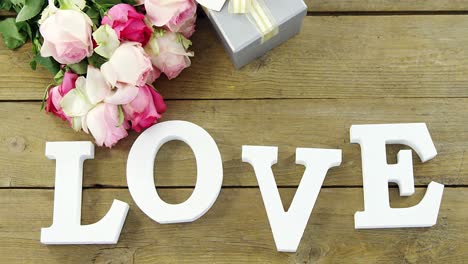 gift box with bunch of roses and love alphabet on wooden plank