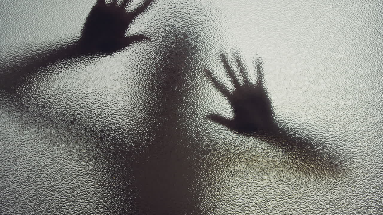 A female silhouette behind the frosted window touches the glass slowly