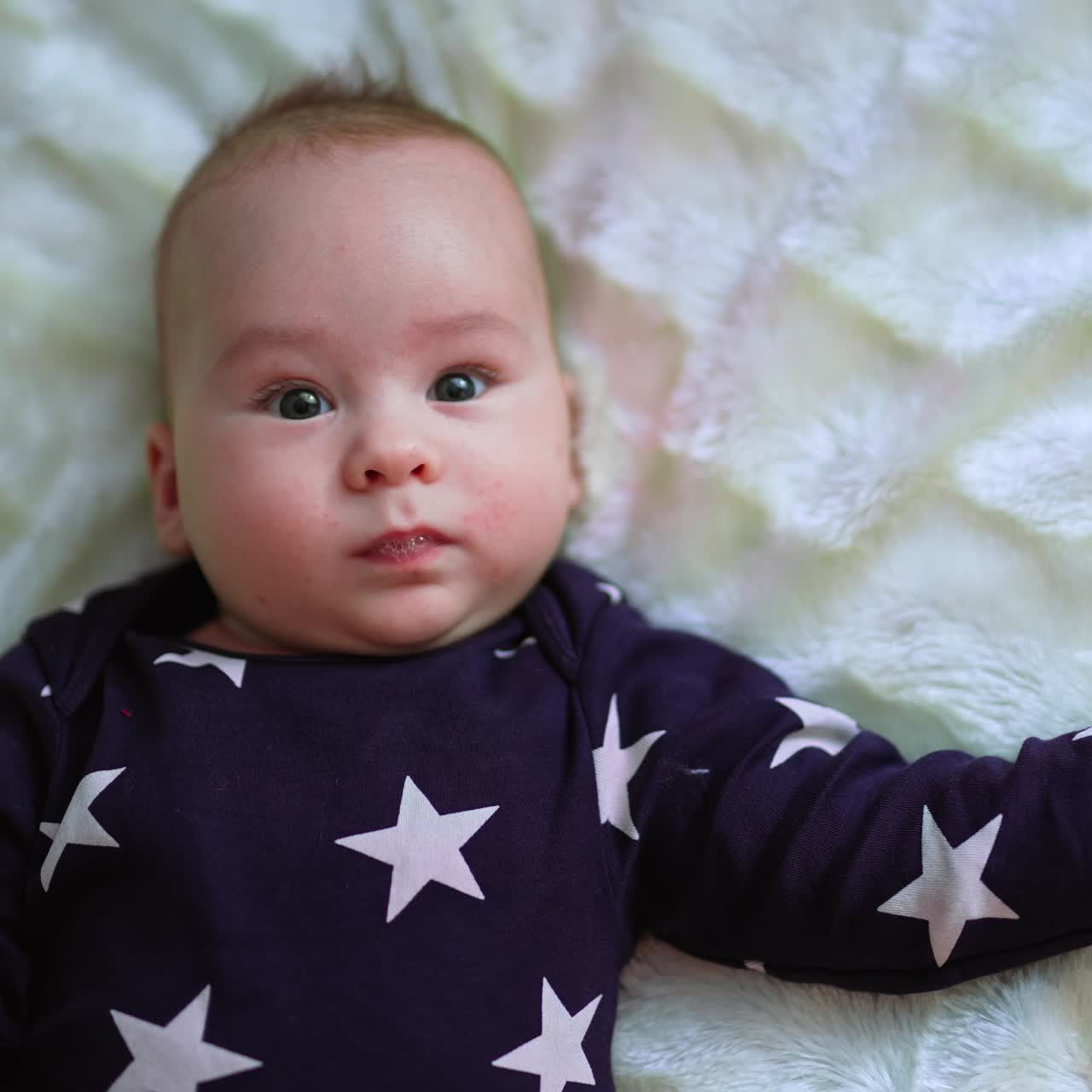 Smiling beautiful toddler being active on the bed. Top view on a nice cute cheerful baby on white backdrop