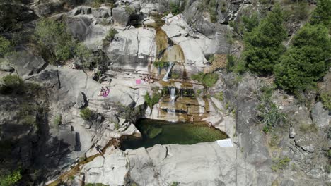 Gente-Relajándose-En-Las-Rocas-Junto-A-La-Piscina-Natural-En-Las-Cascadas-De-Closes-De-Barjas-En-El-Parque-Nacional-De-Peneda-geres,-Portugal